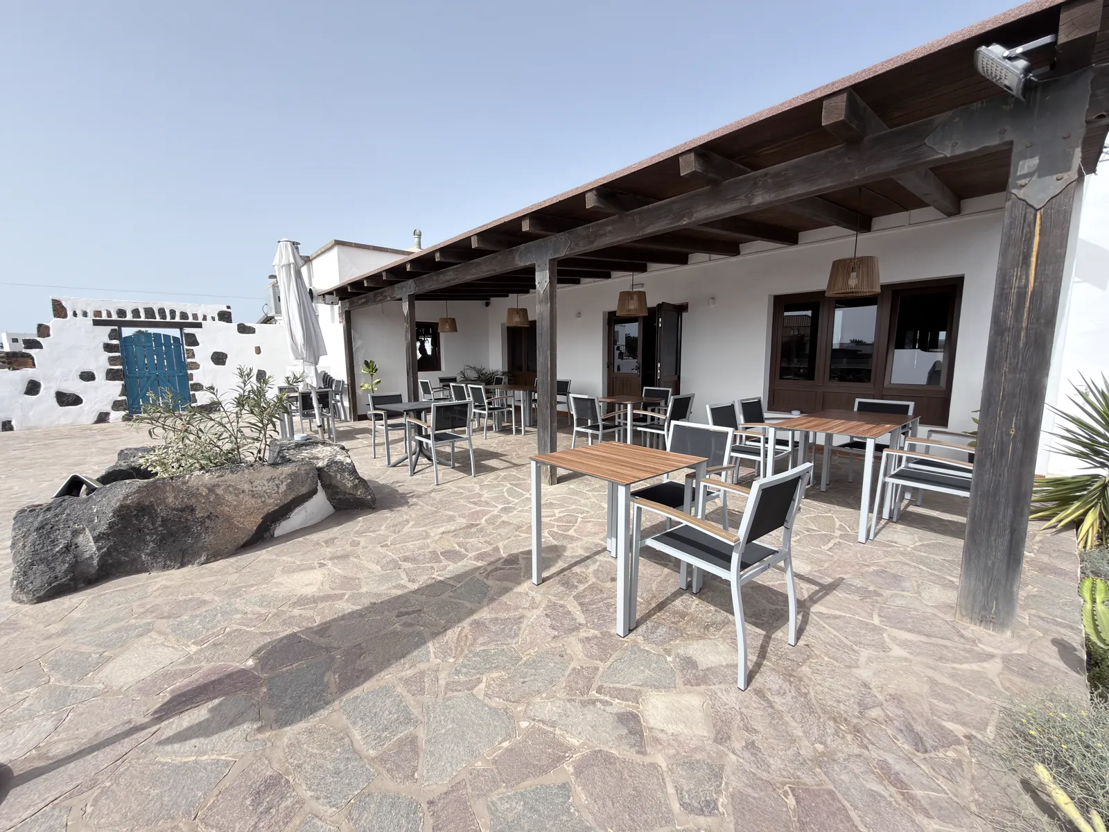 Terraza con pérgola de madera y puerta azul al fondo